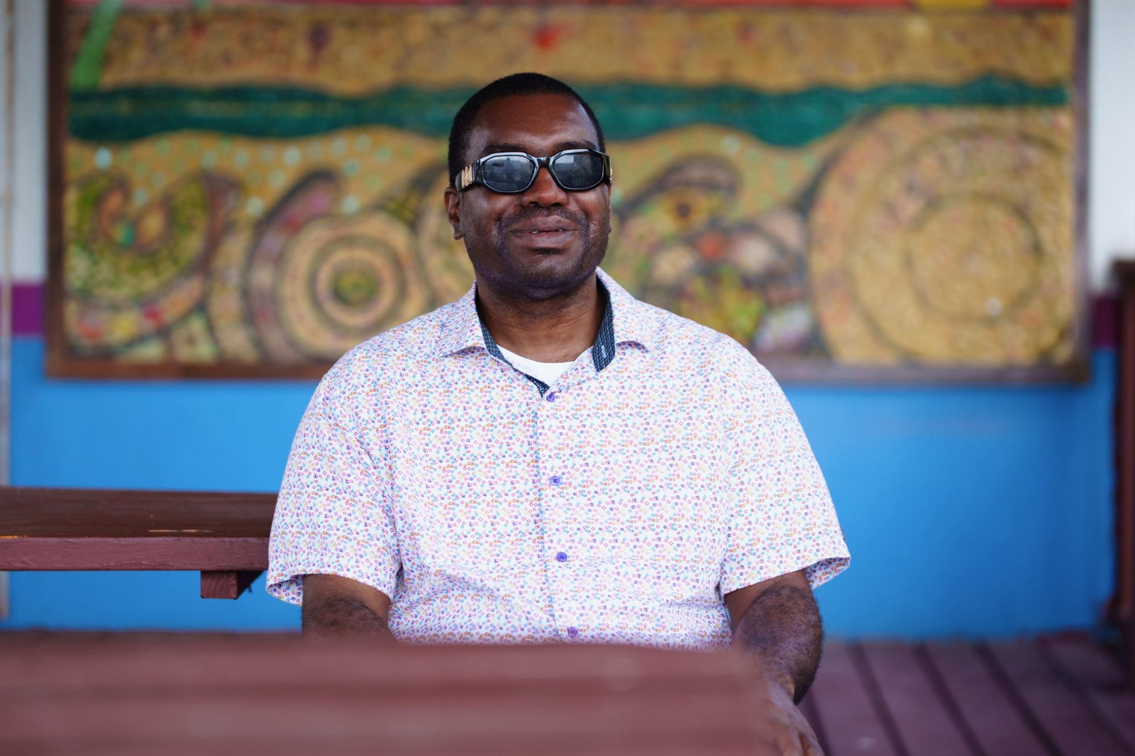 Kevin E. Cartwright seated in front of colourful Bahamian artwork, representing the cultural inspiration behind the Brain Vitamin books.